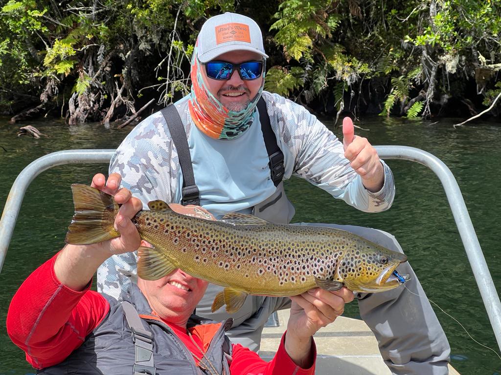 Anglers celebrating a brown trout catch in a boat in Patagonia Chile