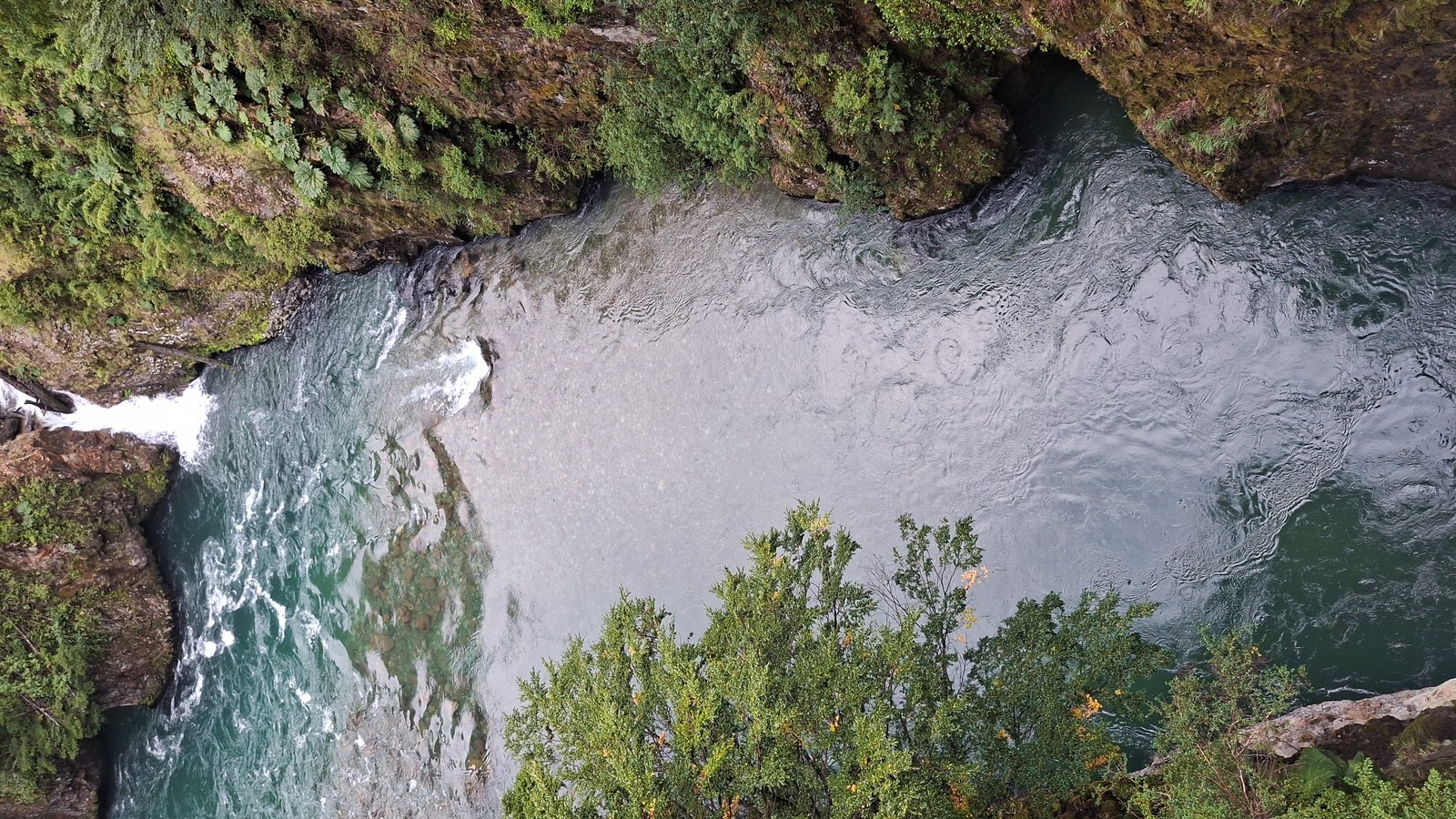 Aerial view of a waterfall feeding a turquoise canyon river in Patagonia Chile