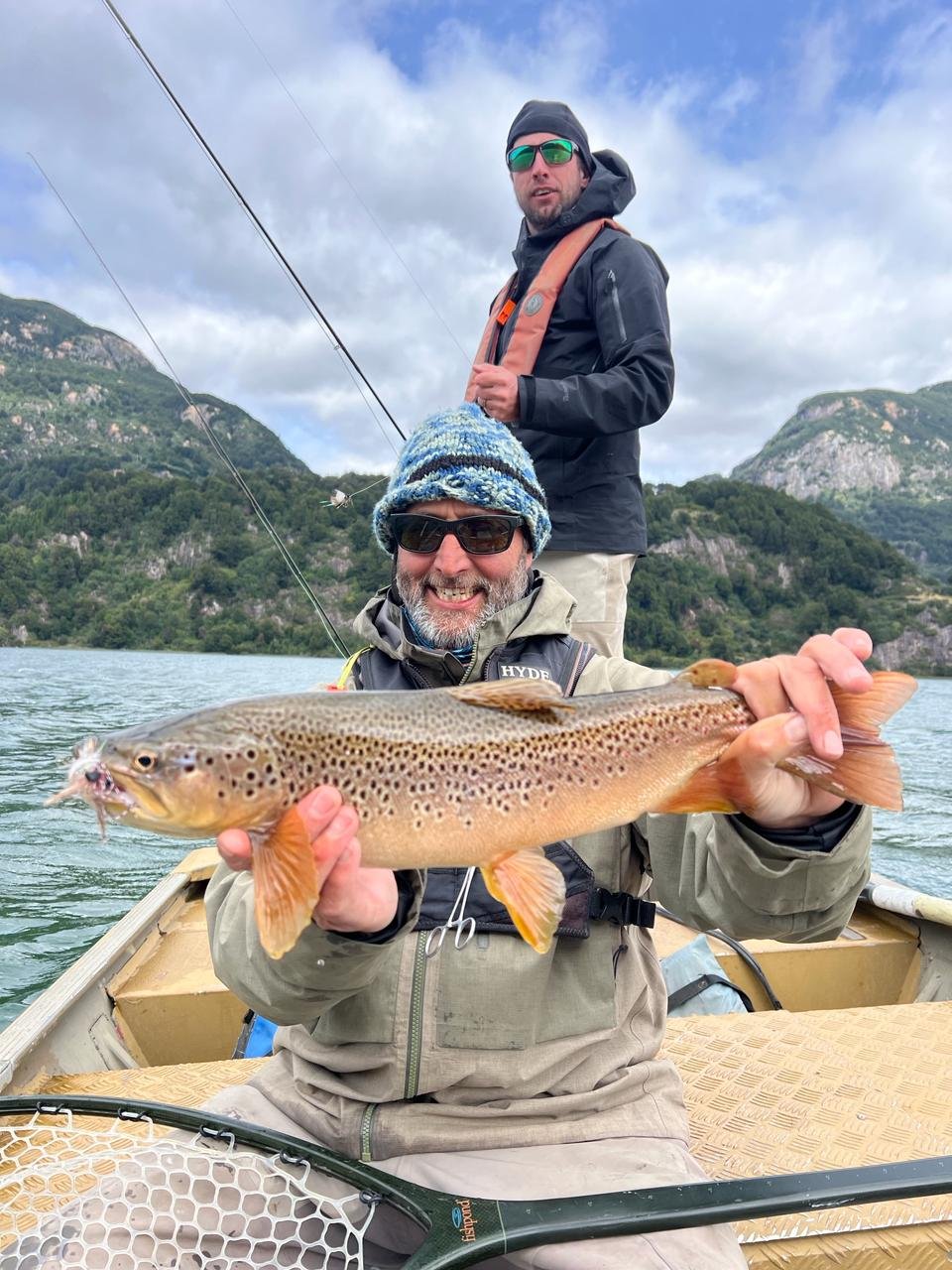 Happy angler with brown trout in a boat — Chile fly fishing trip