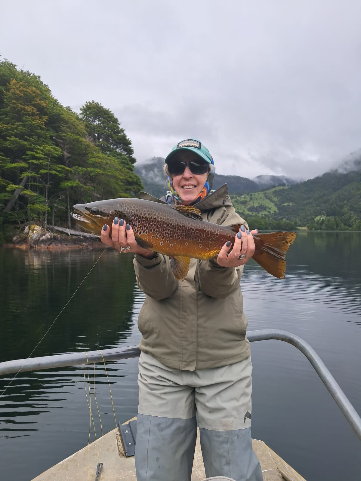Angler with a brown trout on a misty lake in Chilean Patagonia