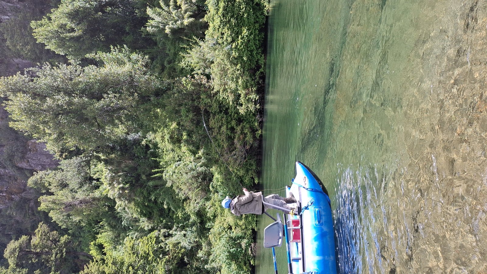Angler casting from a raft over clear green water in Chilean Patagonia